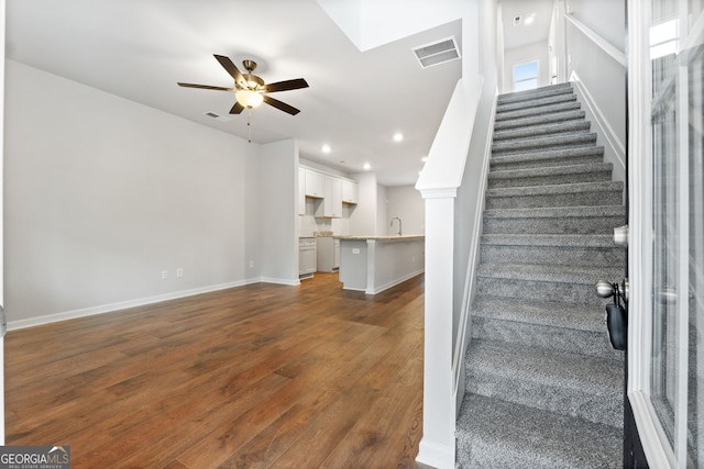 stairway with ceiling fan, sink, and hardwood / wood-style flooring