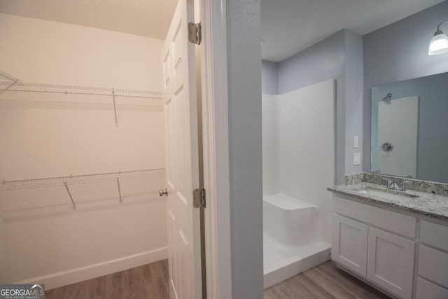 bathroom featuring walk in shower, wood-type flooring, and vanity