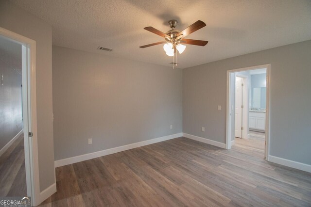 unfurnished room featuring hardwood / wood-style flooring, ceiling fan, and a textured ceiling