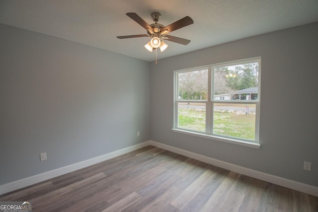 empty room with ceiling fan, light hardwood / wood-style floors, and a textured ceiling
