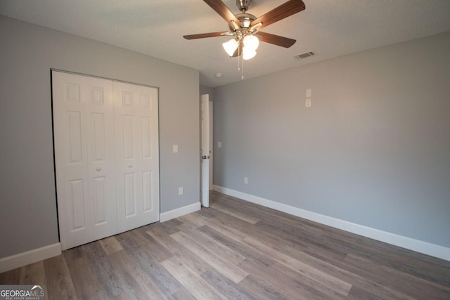 unfurnished bedroom featuring a textured ceiling, a closet, ceiling fan, and light wood-type flooring