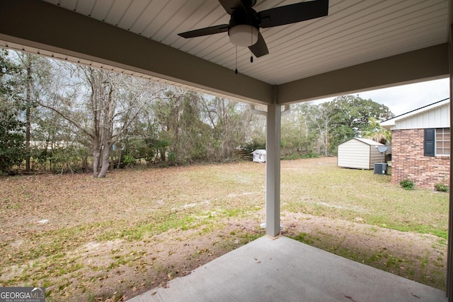 view of yard with ceiling fan, a storage shed, and a patio