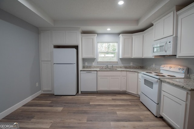 kitchen featuring light wood-type flooring, white appliances, sink, and white cabinets