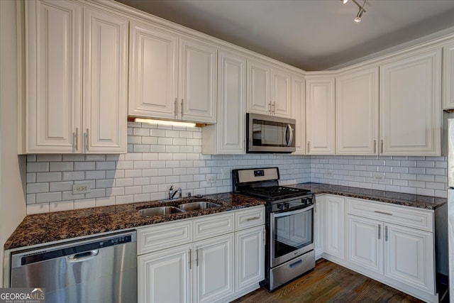 kitchen with dark stone countertops, white cabinetry, dark hardwood / wood-style flooring, stainless steel appliances, and sink