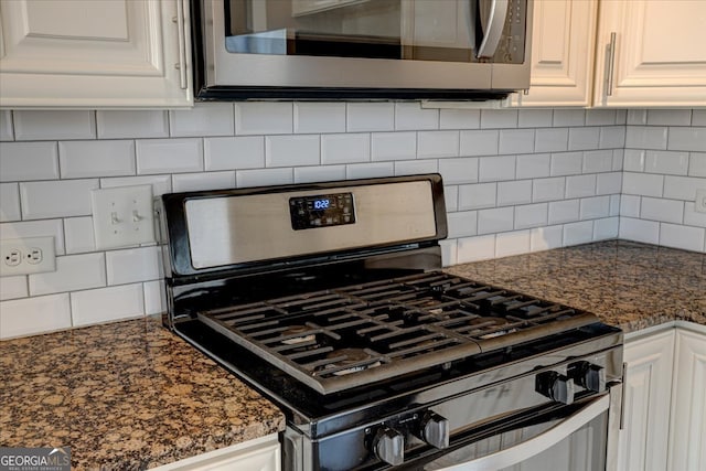 interior details with dark stone countertops, stainless steel appliances, backsplash, and white cabinetry