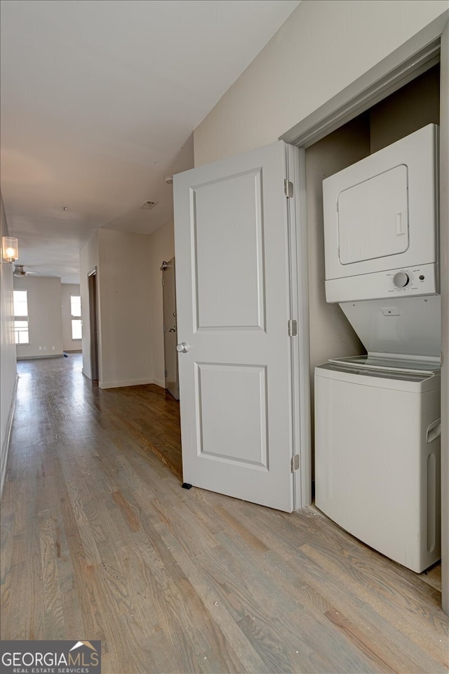 laundry area featuring stacked washer and clothes dryer and light wood-type flooring