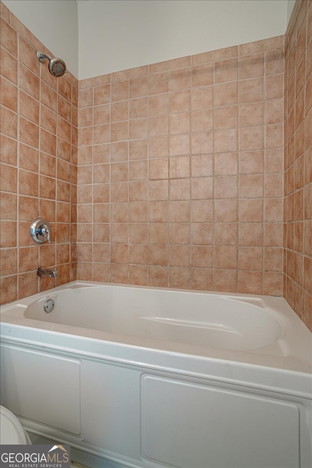 bathroom featuring tiled shower / bath and toilet