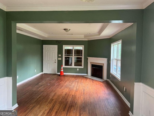 unfurnished living room with a tray ceiling, crown molding, and dark wood-type flooring