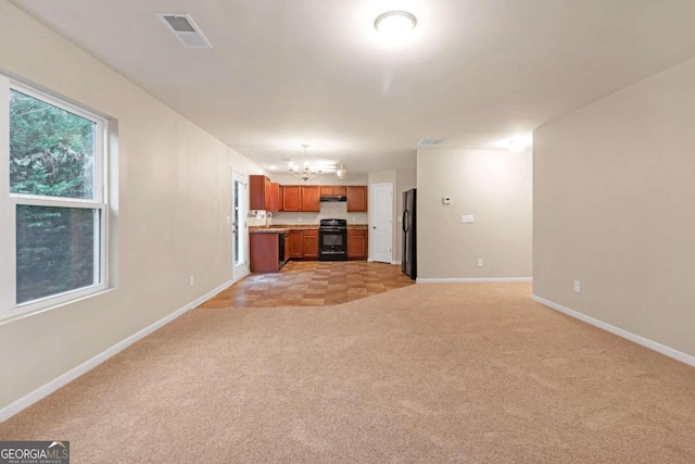 unfurnished living room featuring a notable chandelier and light colored carpet