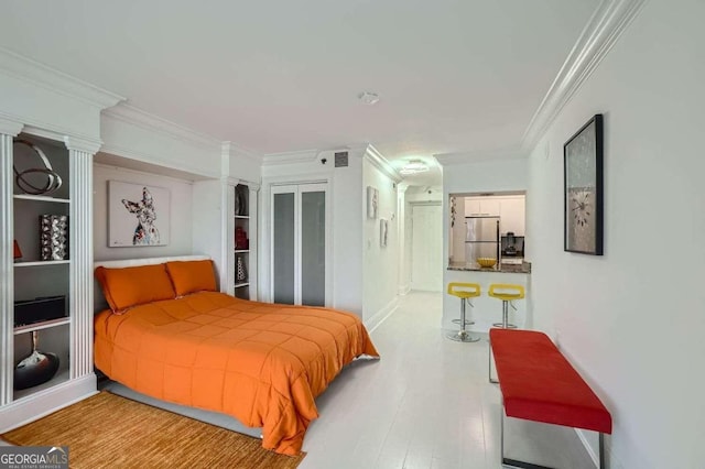 bedroom featuring stainless steel refrigerator, ornamental molding, hardwood / wood-style floors, and a closet