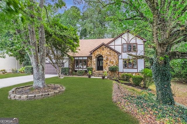 english style home featuring a garage and a front lawn