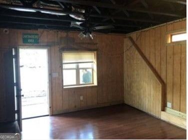 interior space featuring wooden walls, dark hardwood / wood-style floors, and a healthy amount of sunlight