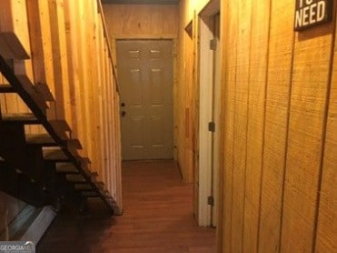 hall with wood-type flooring and wooden walls