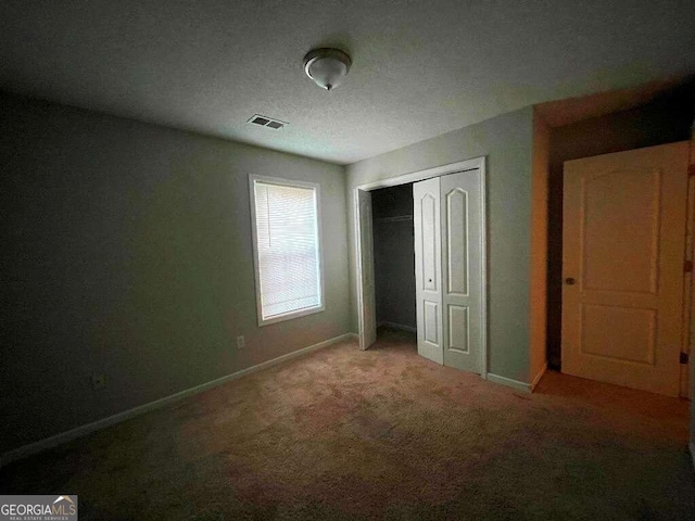 unfurnished bedroom featuring a closet, carpet flooring, and a textured ceiling