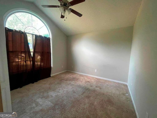 unfurnished room with a textured ceiling, vaulted ceiling, light carpet, and ceiling fan