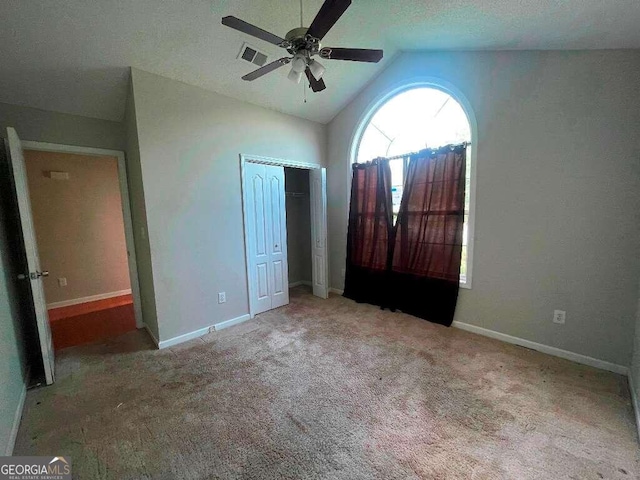 unfurnished bedroom featuring a textured ceiling, lofted ceiling, ceiling fan, and light colored carpet