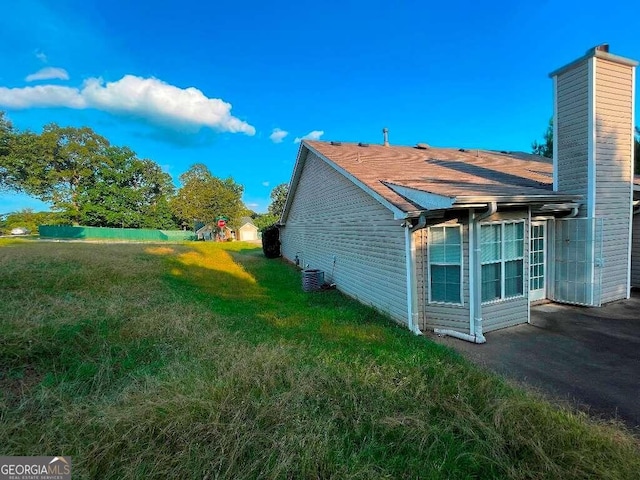 view of property exterior with central AC and a yard