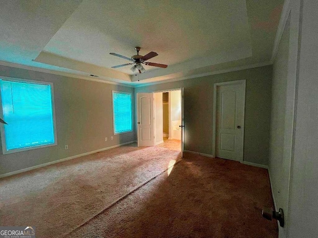 unfurnished bedroom with a raised ceiling, carpet, and ceiling fan