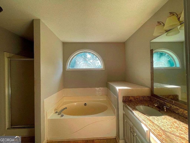 bathroom featuring plus walk in shower, a textured ceiling, and vanity