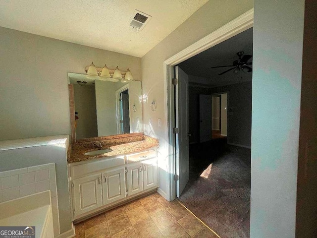 bathroom featuring ceiling fan, vanity, a bath, and a textured ceiling