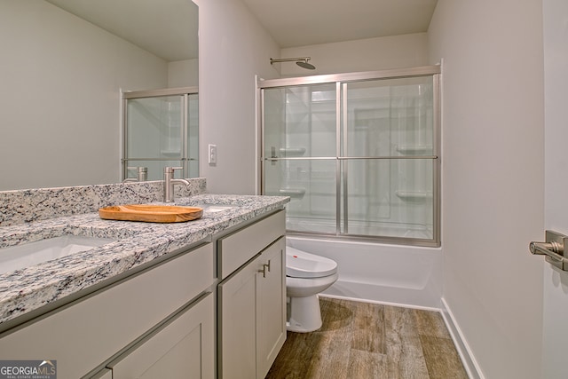 full bathroom with shower / bath combination with glass door, vanity, hardwood / wood-style floors, and toilet