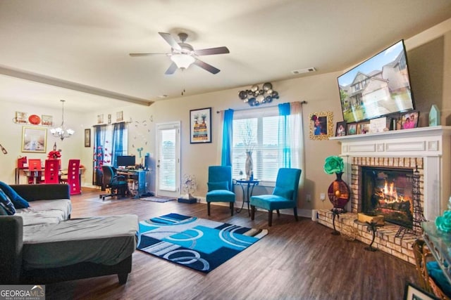 living room featuring wood-type flooring, ceiling fan with notable chandelier, and a fireplace