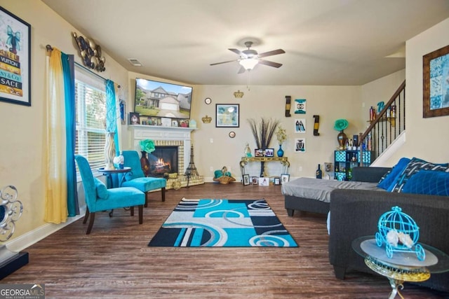 living room featuring ceiling fan, a fireplace, and wood-type flooring