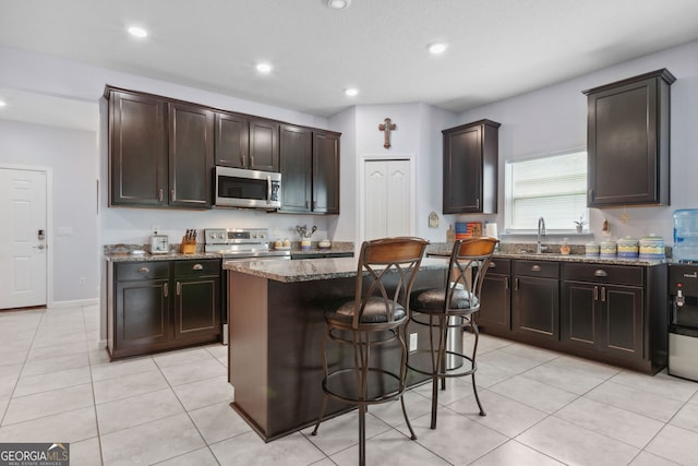 kitchen with dark brown cabinets, appliances with stainless steel finishes, a kitchen island, and sink