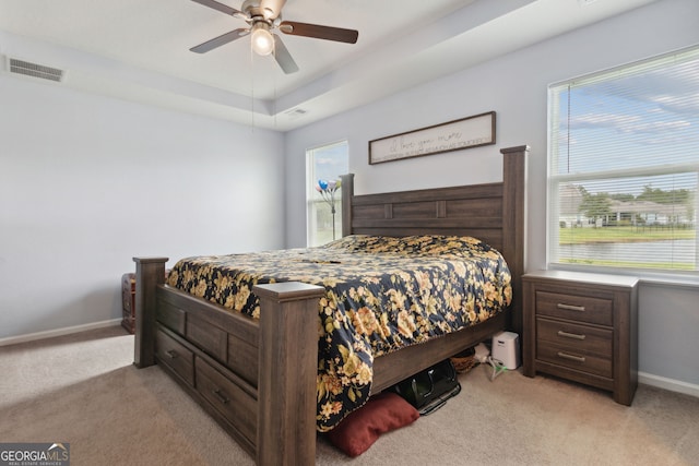 carpeted bedroom with a tray ceiling and ceiling fan