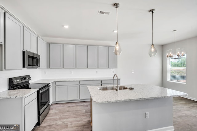 kitchen featuring tasteful backsplash, visible vents, stainless steel appliances, light wood-type flooring, and a sink