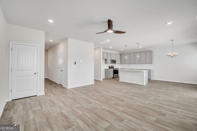 unfurnished living room with light wood-style floors, recessed lighting, a sink, and ceiling fan with notable chandelier