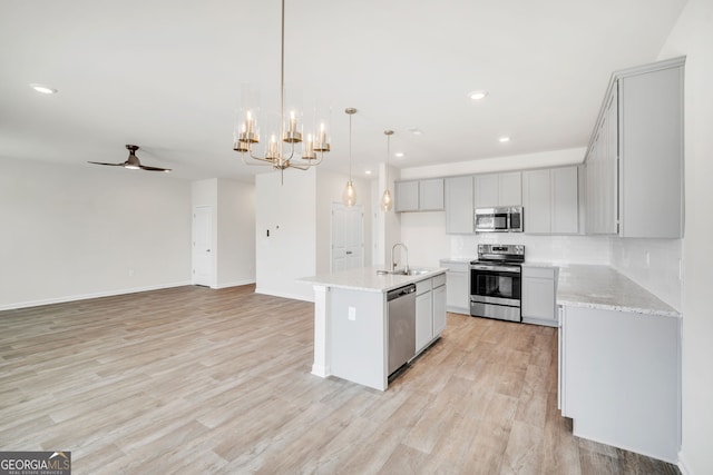 kitchen featuring ceiling fan with notable chandelier, stainless steel appliances, a sink, light wood-style floors, and gray cabinets