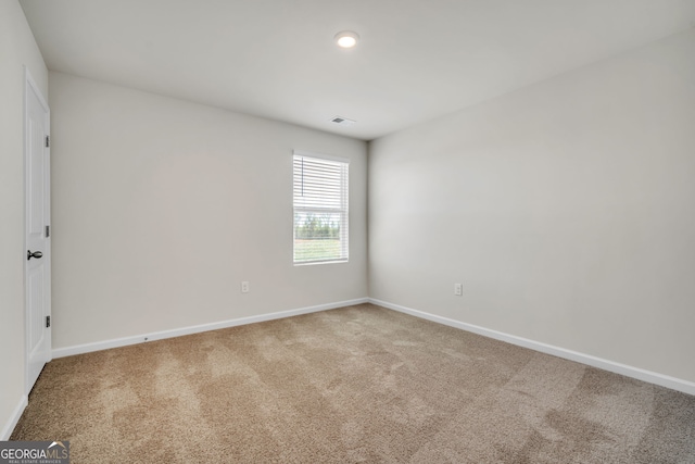 spare room featuring carpet, visible vents, and baseboards