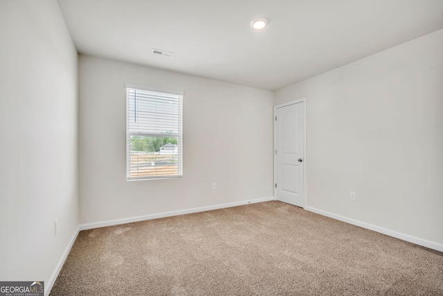 empty room with light carpet, visible vents, and baseboards