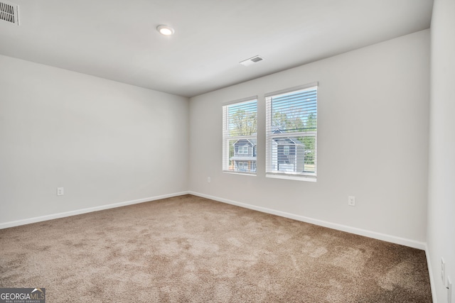 carpeted spare room with visible vents and baseboards