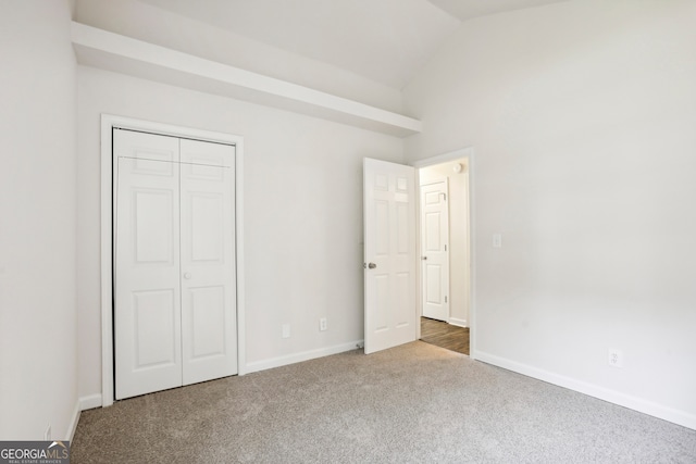 unfurnished bedroom with lofted ceiling, carpet flooring, and a closet