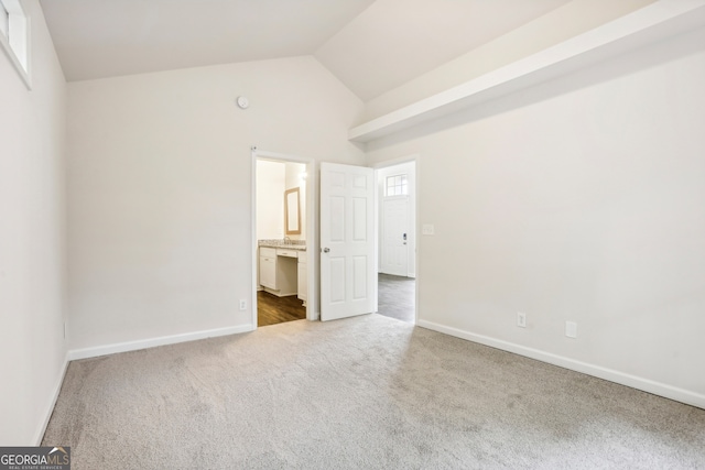 unfurnished bedroom featuring connected bathroom, carpet, and high vaulted ceiling