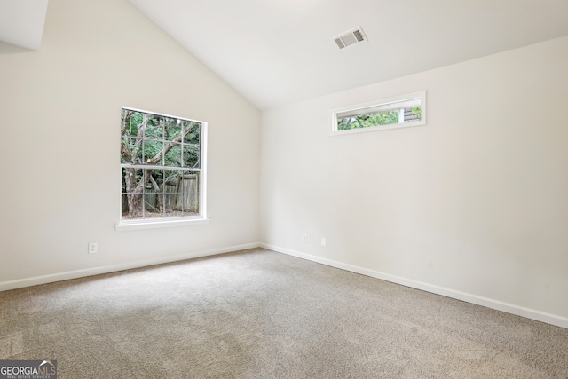 carpeted empty room with high vaulted ceiling and a healthy amount of sunlight