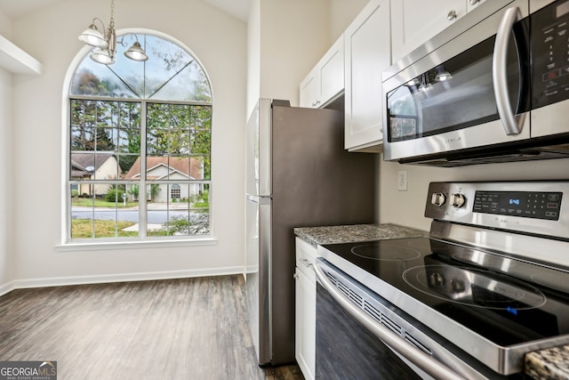 kitchen with a chandelier, dark hardwood / wood-style floors, white cabinets, lofted ceiling, and appliances with stainless steel finishes