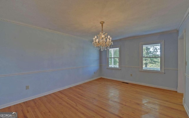 unfurnished room featuring ornamental molding, light hardwood / wood-style flooring, and a chandelier