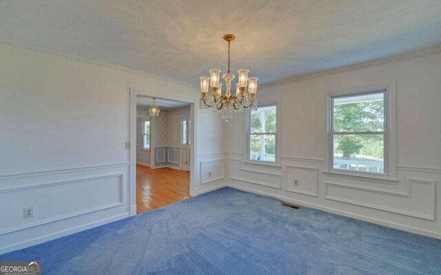 spare room with wood-type flooring, ornamental molding, and a notable chandelier