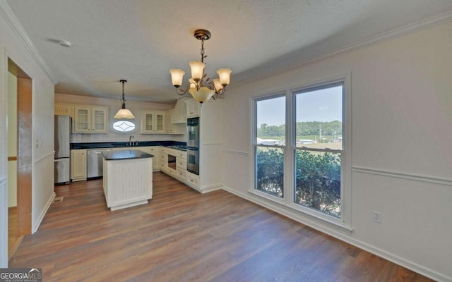 kitchen with appliances with stainless steel finishes, dark wood-type flooring, pendant lighting, crown molding, and a center island