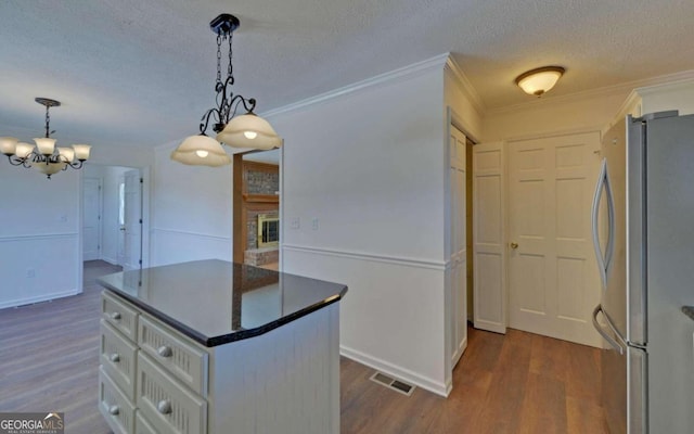 kitchen with ornamental molding, a center island, dark wood-type flooring, and stainless steel fridge