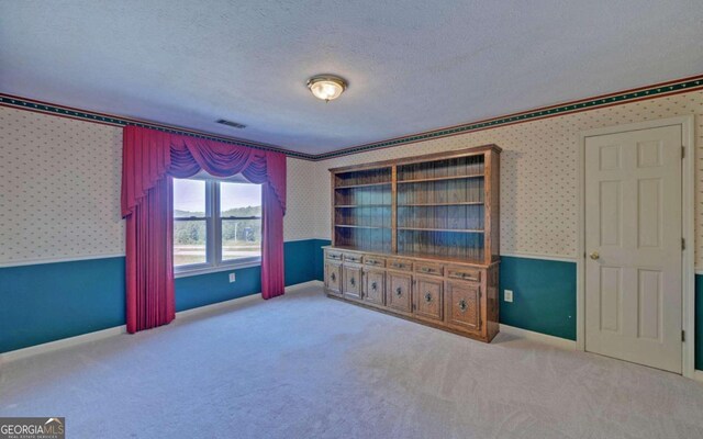 unfurnished bedroom featuring light carpet and a textured ceiling