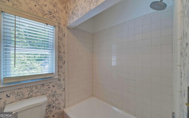 bathroom featuring toilet and tiled shower / bath