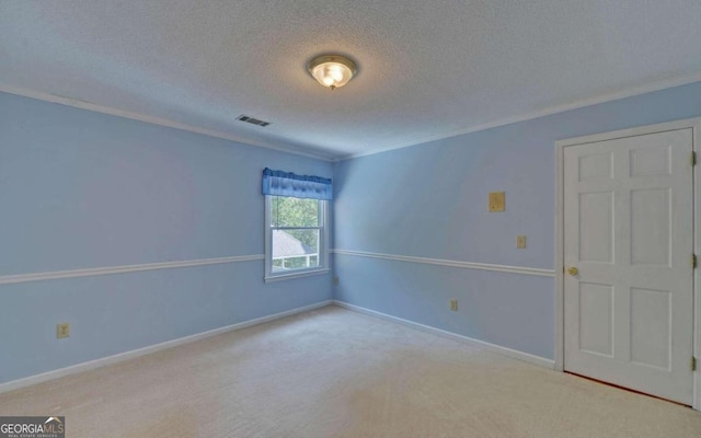 spare room with light colored carpet, a textured ceiling, and ornamental molding