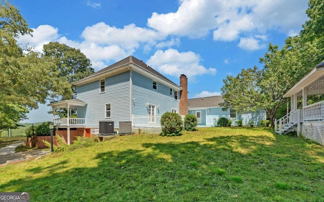 rear view of property with a yard and central air condition unit