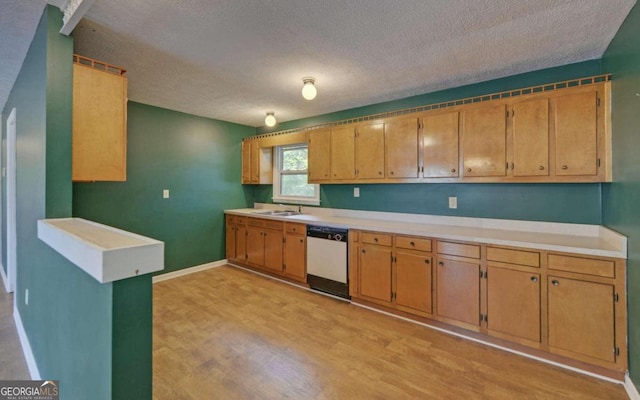 kitchen featuring dishwasher, light wood-type flooring, sink, and a textured ceiling