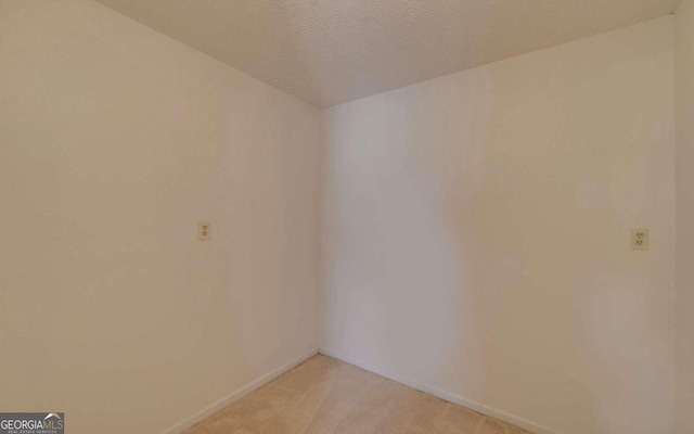 spare room featuring a textured ceiling and light colored carpet