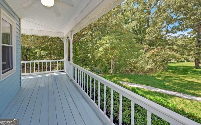 wooden terrace with ceiling fan and a lawn